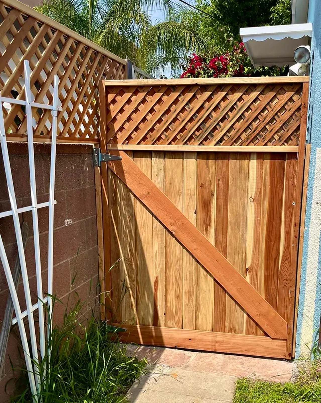 A wooden gate is sitting next to a brick wall.