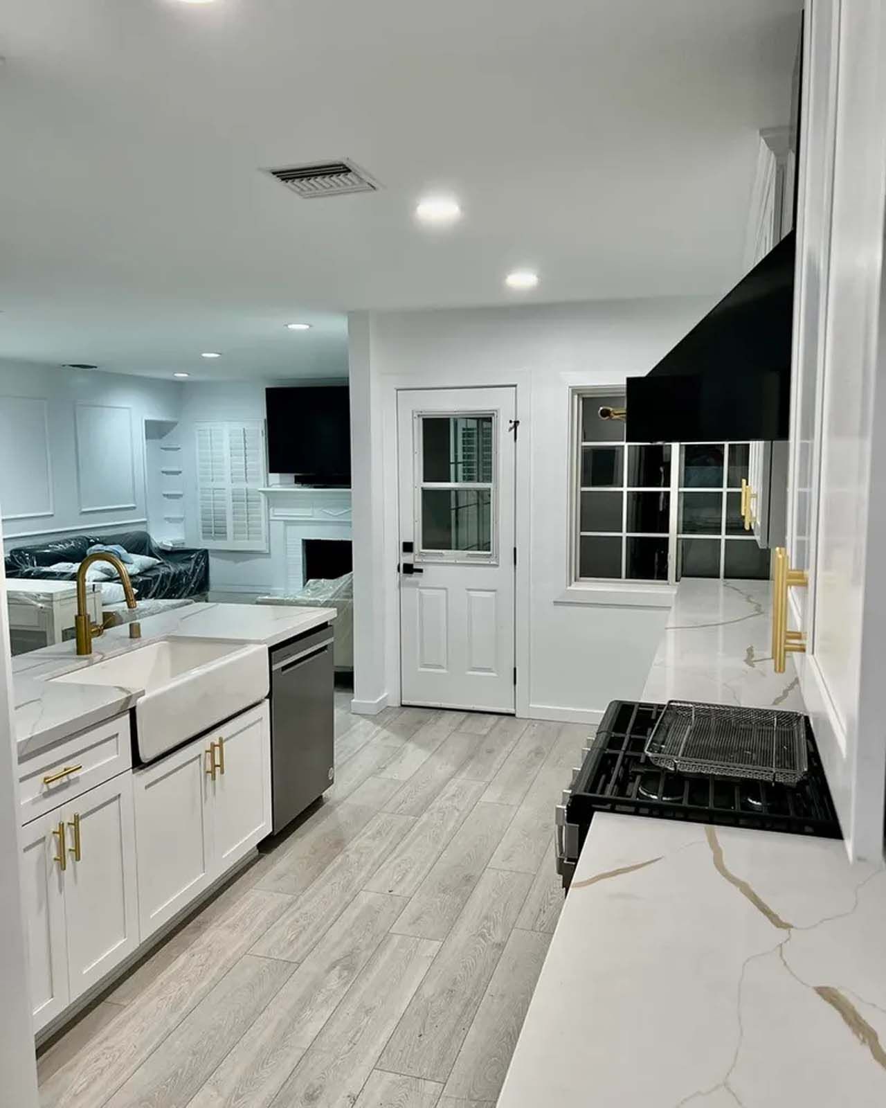 A kitchen with white cabinets , a sink , a stove , and a dishwasher.