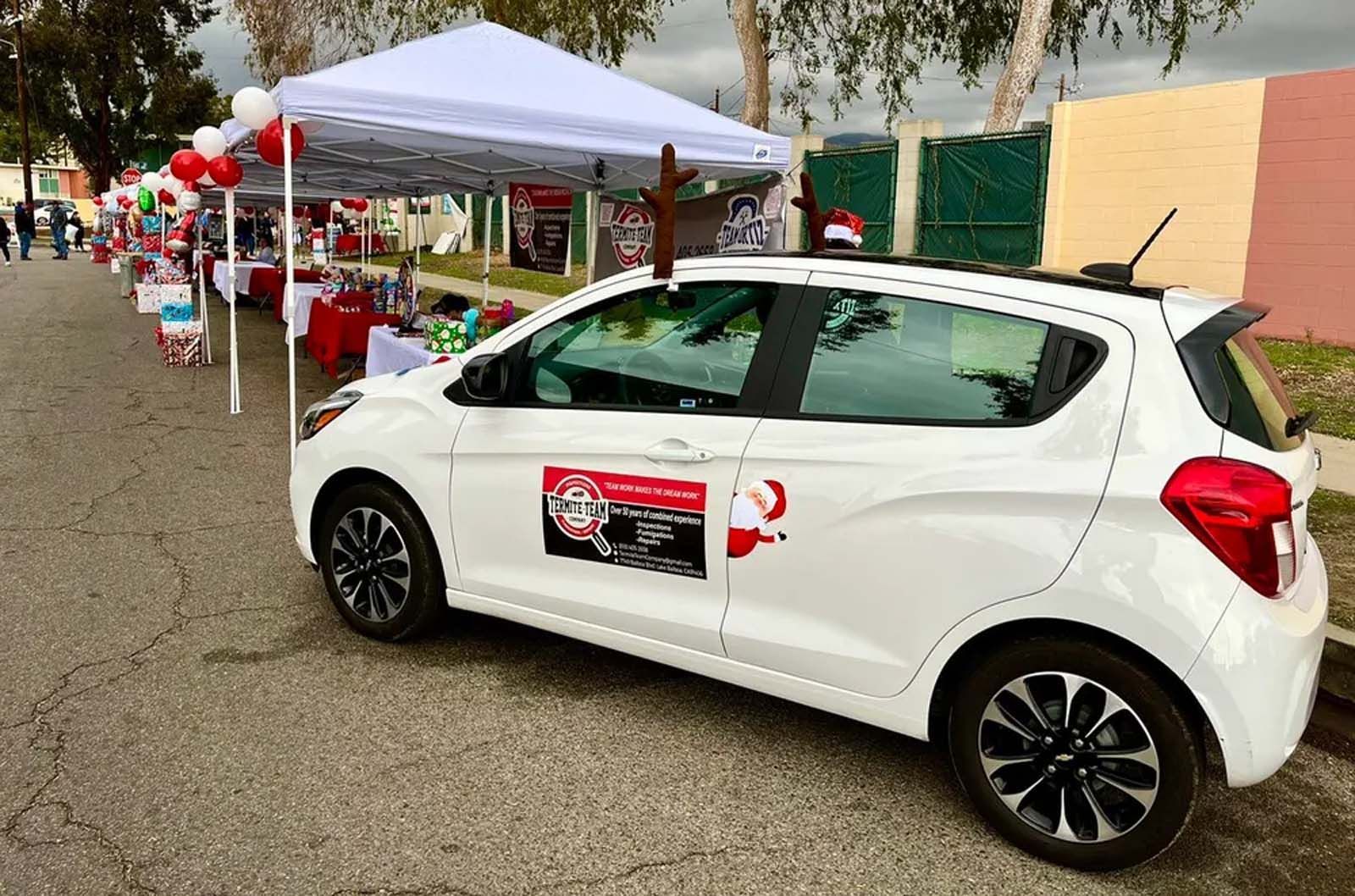 A white car is parked in front of a white tent.