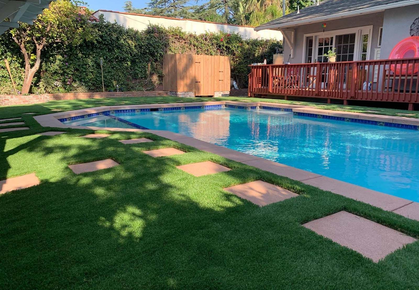 There is a large swimming pool in the backyard of a house.