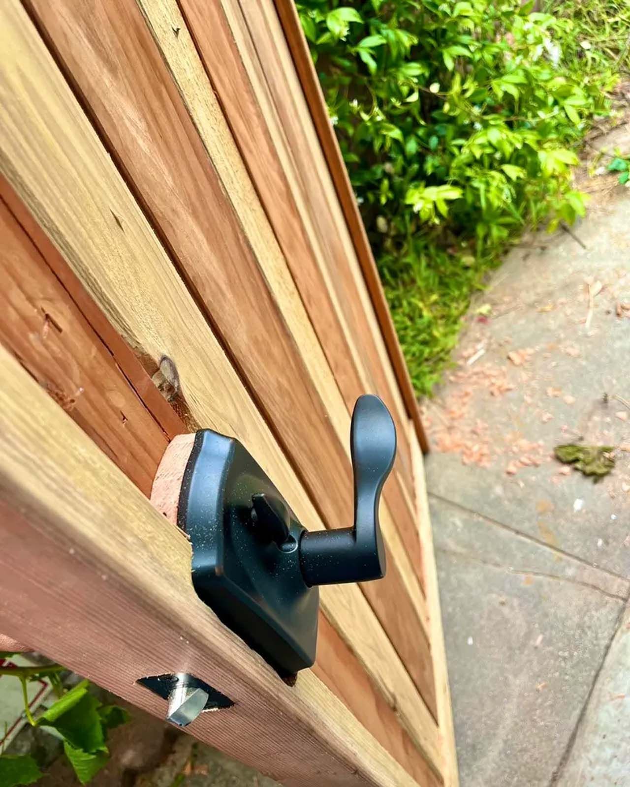 A close up of a black door handle on a wooden door.