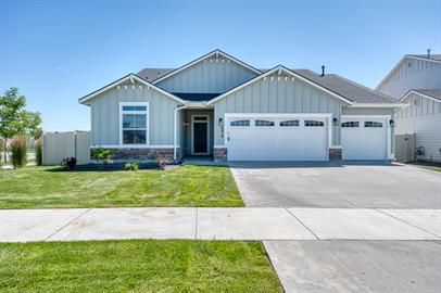 Light blue house with a three-car garage, green lawn, and blue sky.