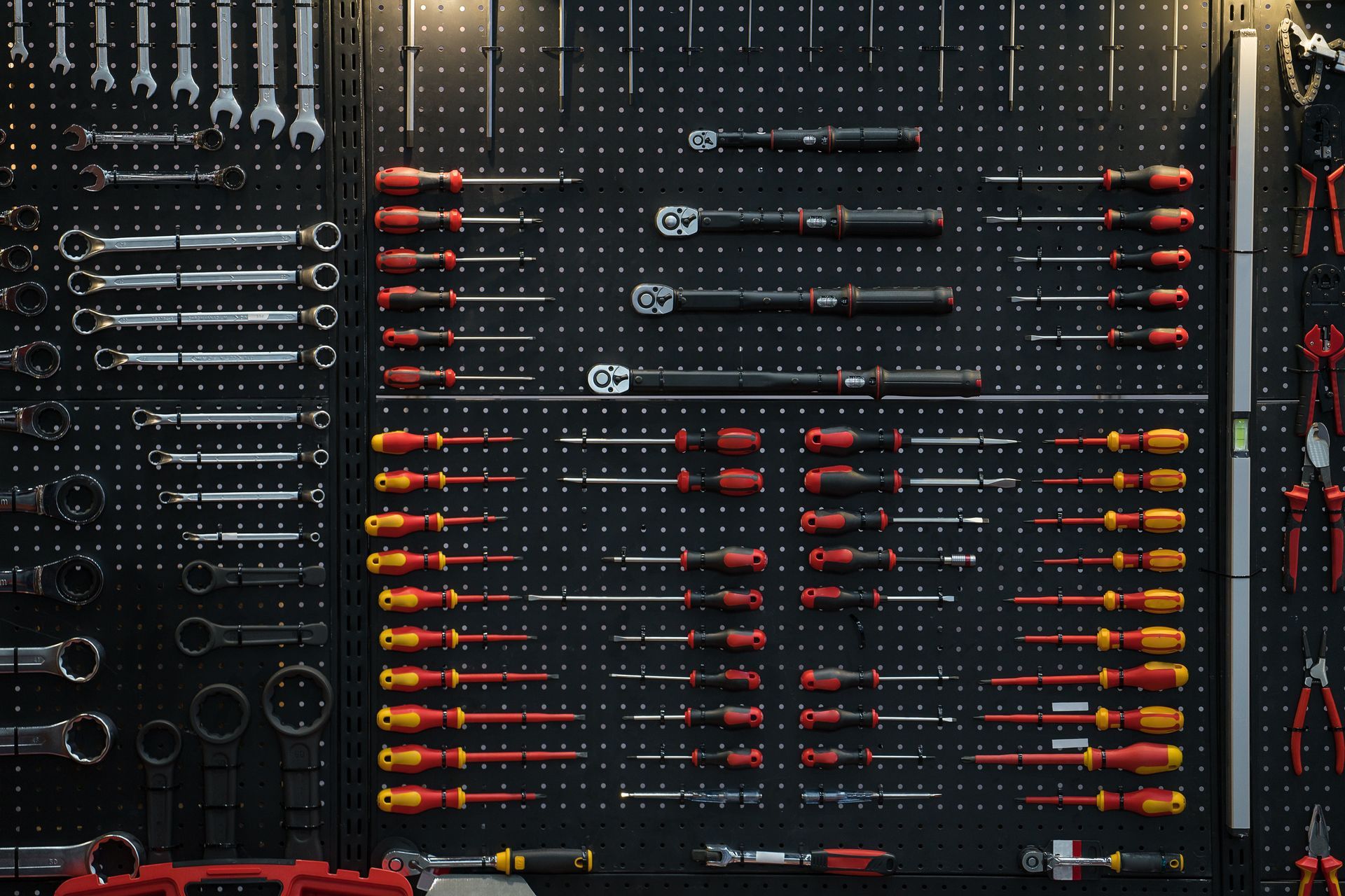 Black pegboard with rows of tools, including wrenches, screwdrivers, and torque wrenches, in a workshop setting.
