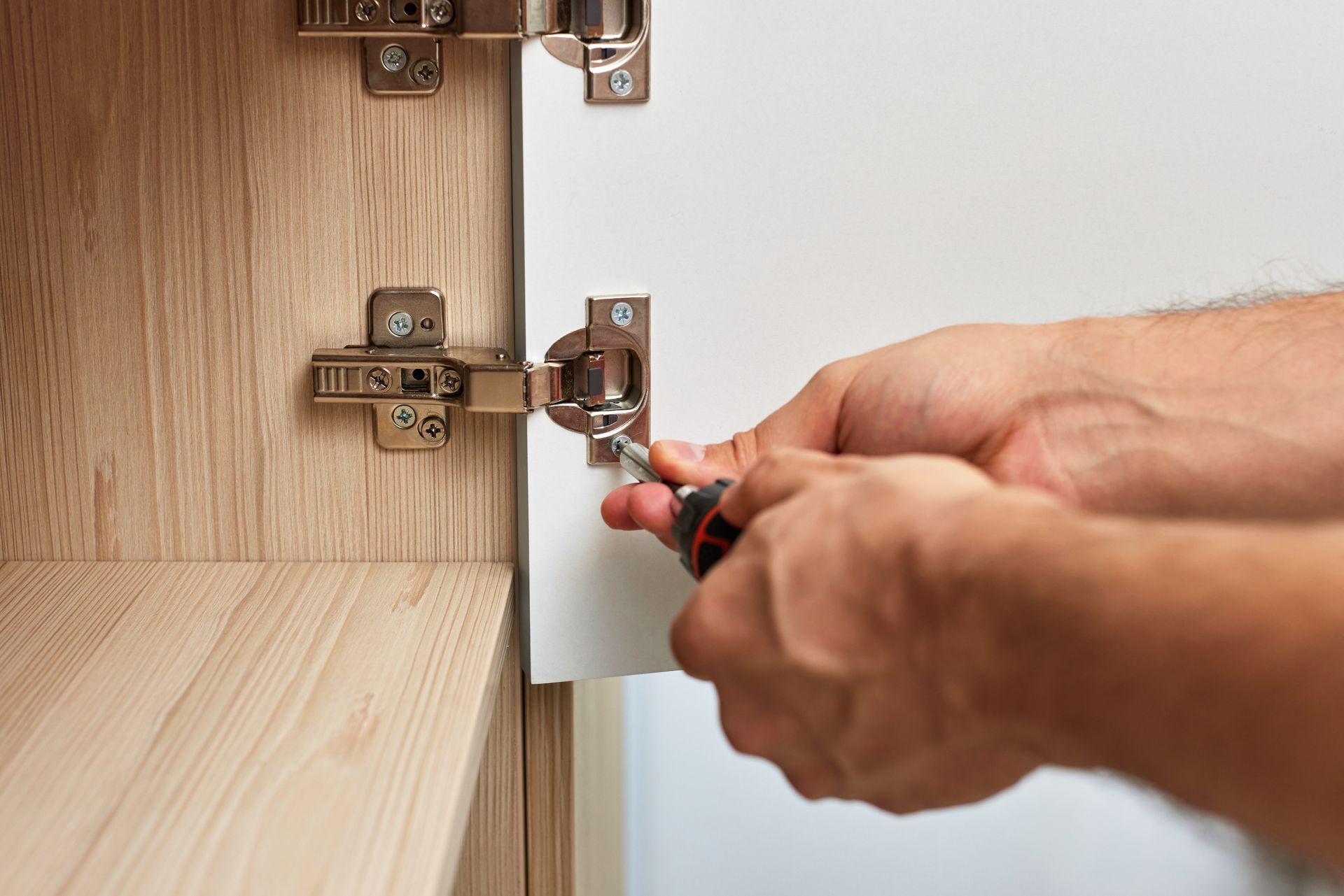 Open toolbox with a cordless drill and various drill bits and accessories on a gray surface.