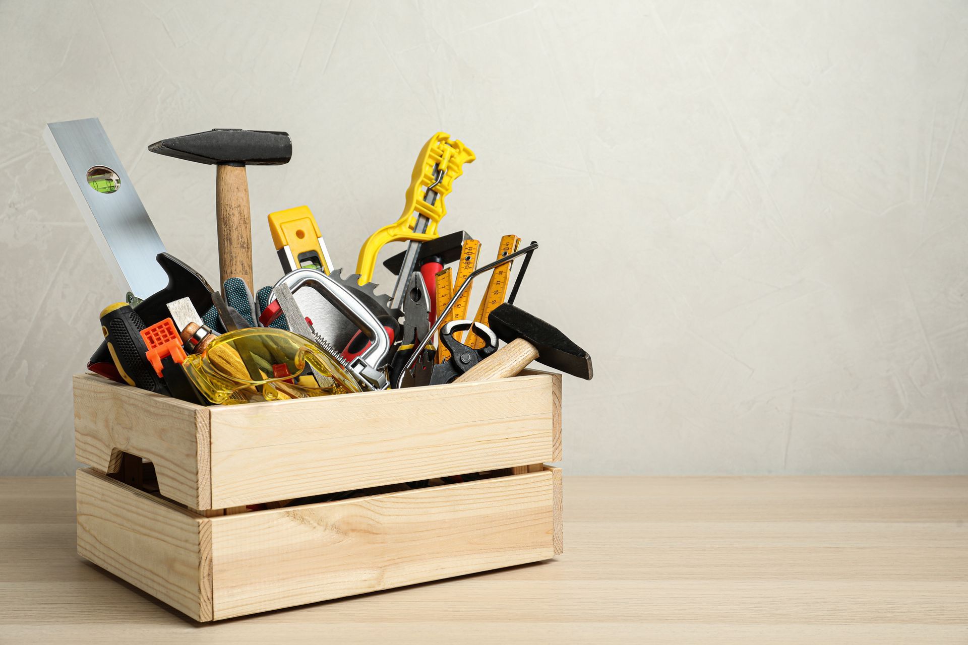 Wooden toolbox filled with various hand tools on a wooden surface.