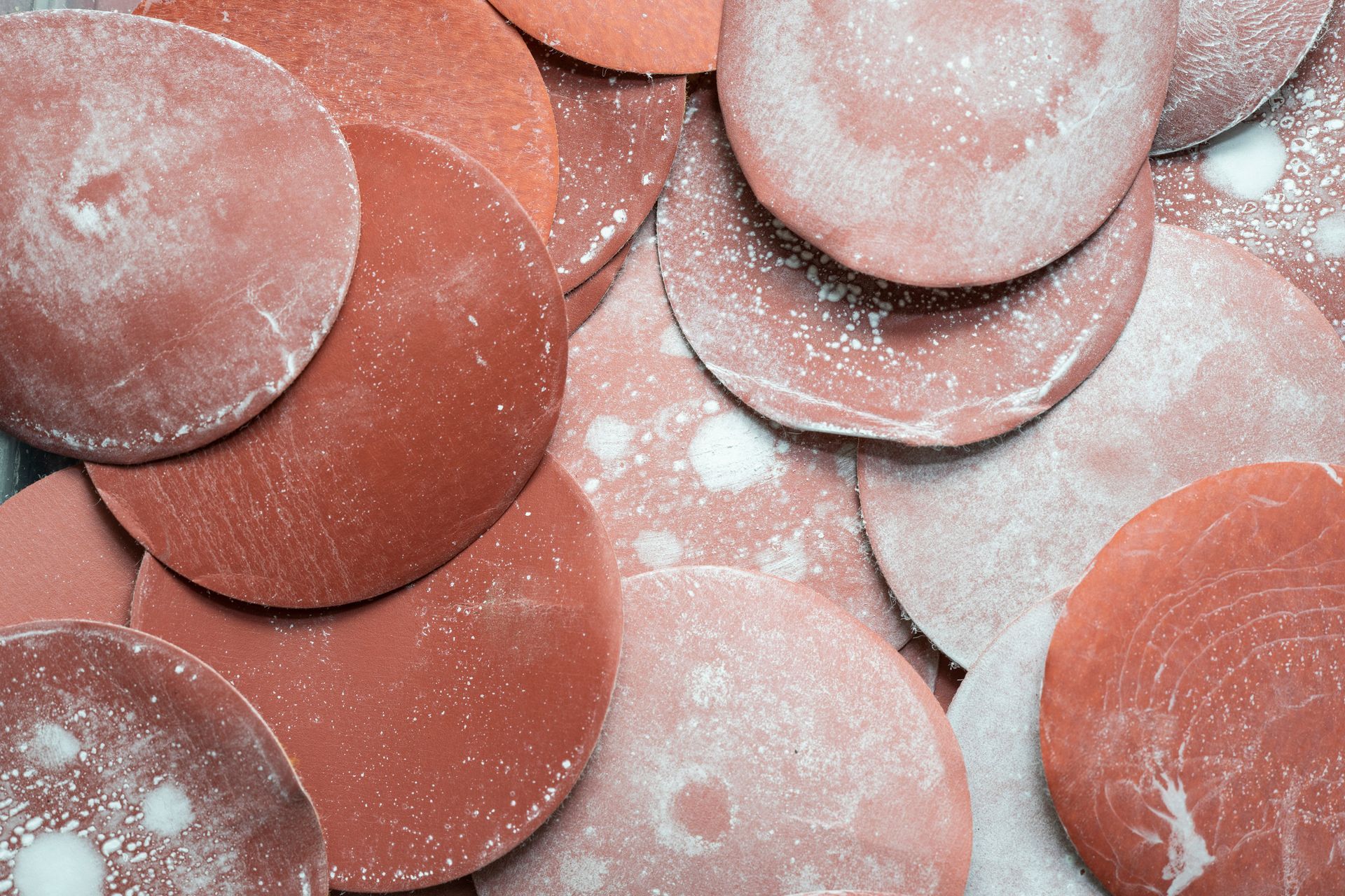 Man looking at paint brushes in a hardware store. He holds one in each hand, confused, near shelves of paint supplies.