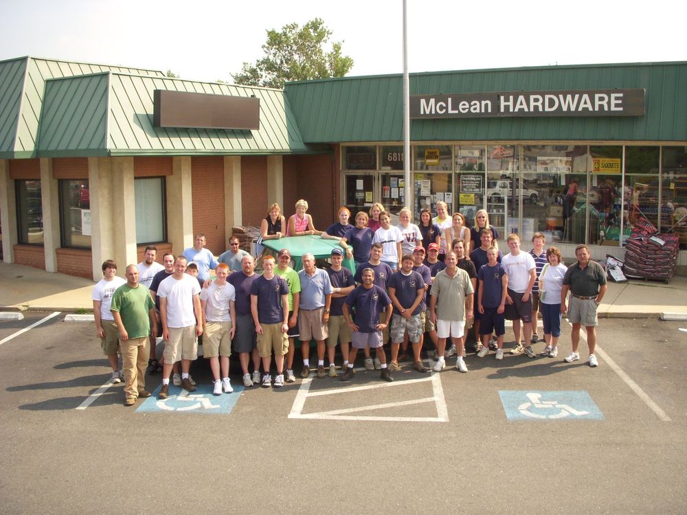 Hardware store employee assisting a couple selecting faucets. Shelves of products.