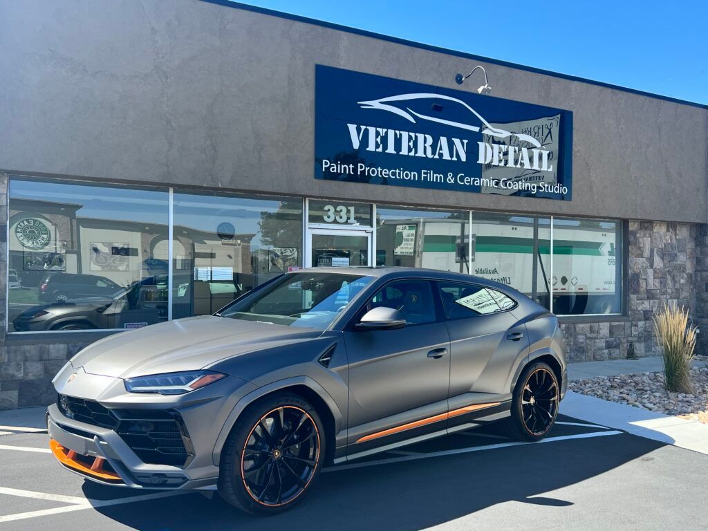 a lamborghini urus is parked in front of a veteran detail shop