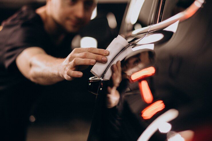 a man is applying ceramic coating on a car with a cloth