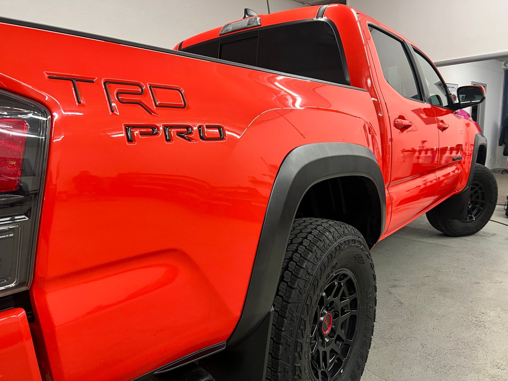 A red toyota tacoma truck is parked in a garage.