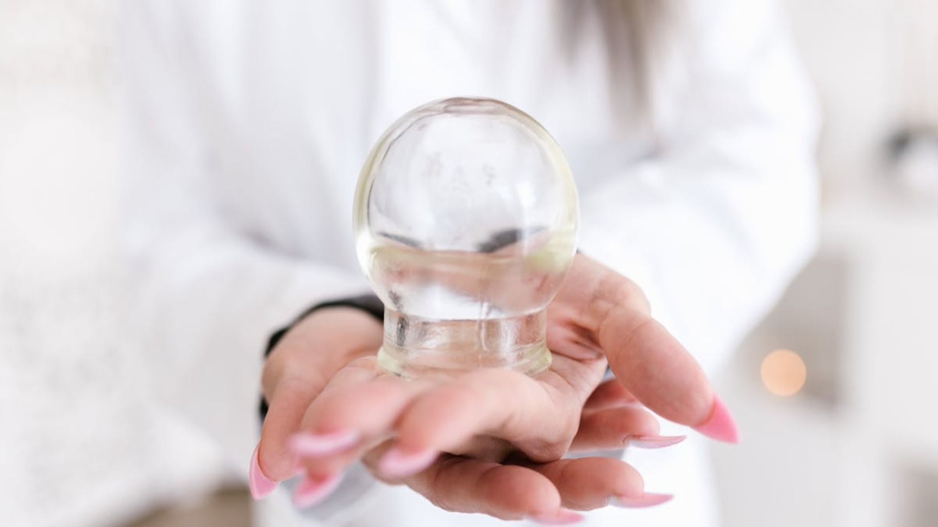 Persona sosteniendo un dispositivo de terapia con ventosas de vidrio transparente.