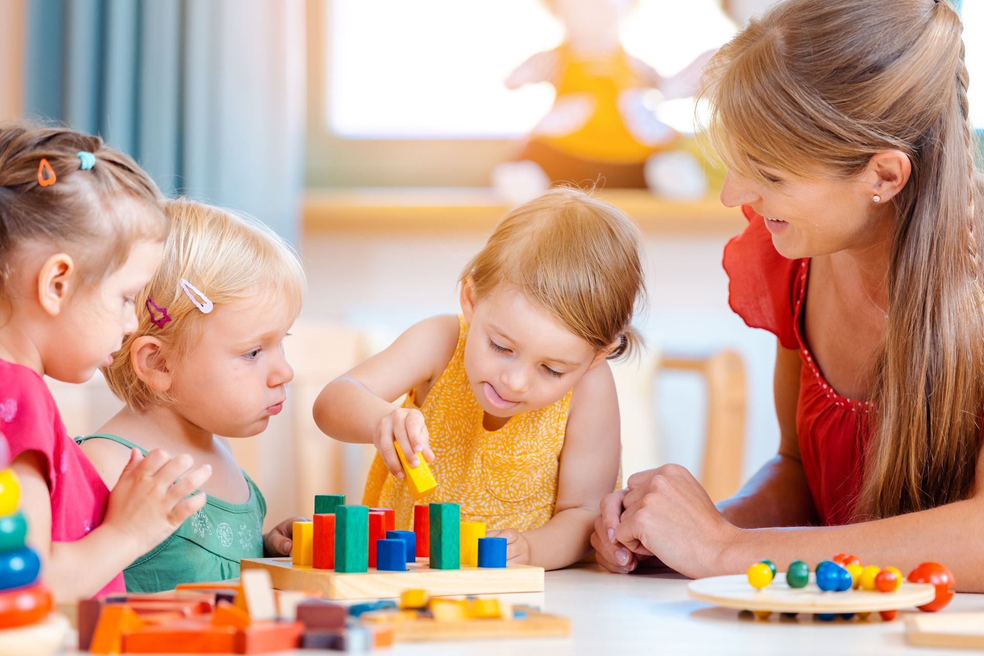 Group of children and female teacher playing in kindergarten. Group of children and female teacher playing in kindergarten.