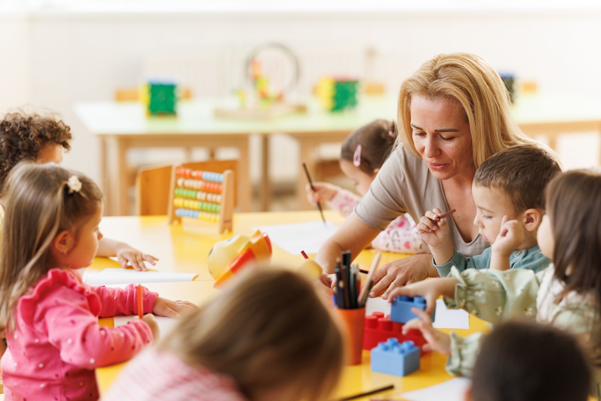 The kindergarten teacher draws together with the children.