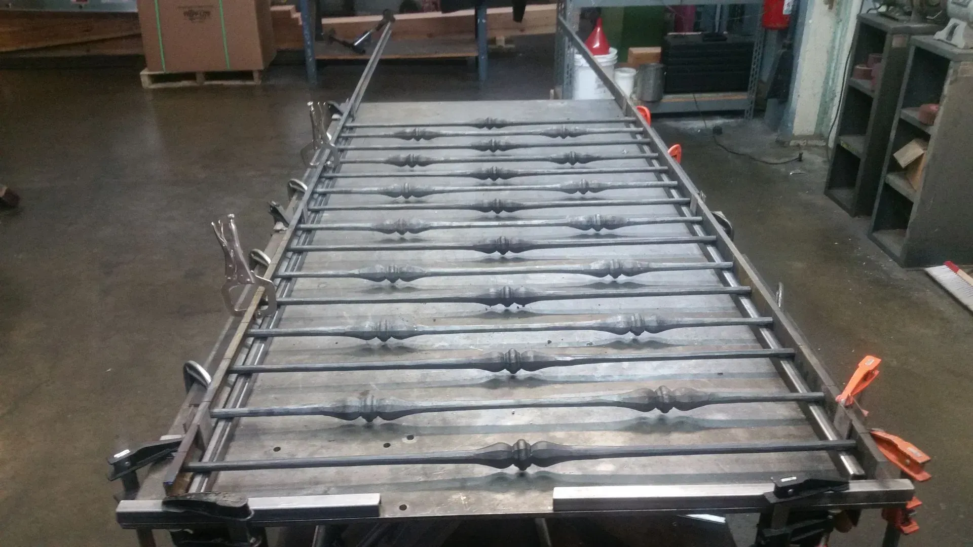 Metalwork fabrication on a table, consisting of horizontal and vertical bars and decorative elements.