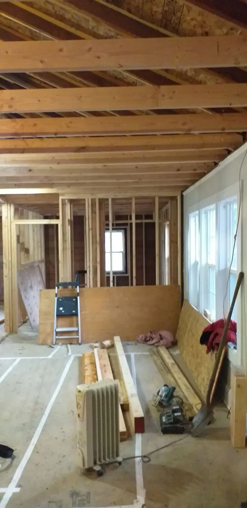 Interior of a building under construction, showing exposed beams, framing, and construction materials.