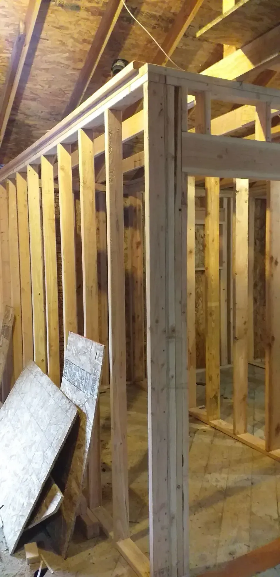 Interior framing of a room under construction, with wooden studs and exposed rafters.