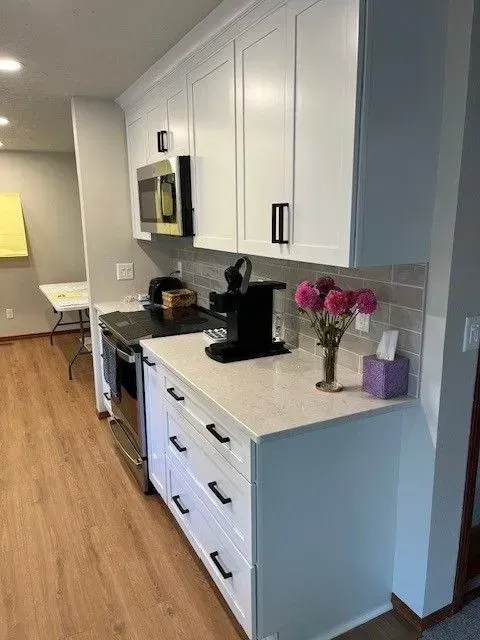 White kitchen cabinets with black hardware and a microwave.