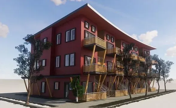 Multi-story red building with wooden balconies; street-side trees; light blue sky.