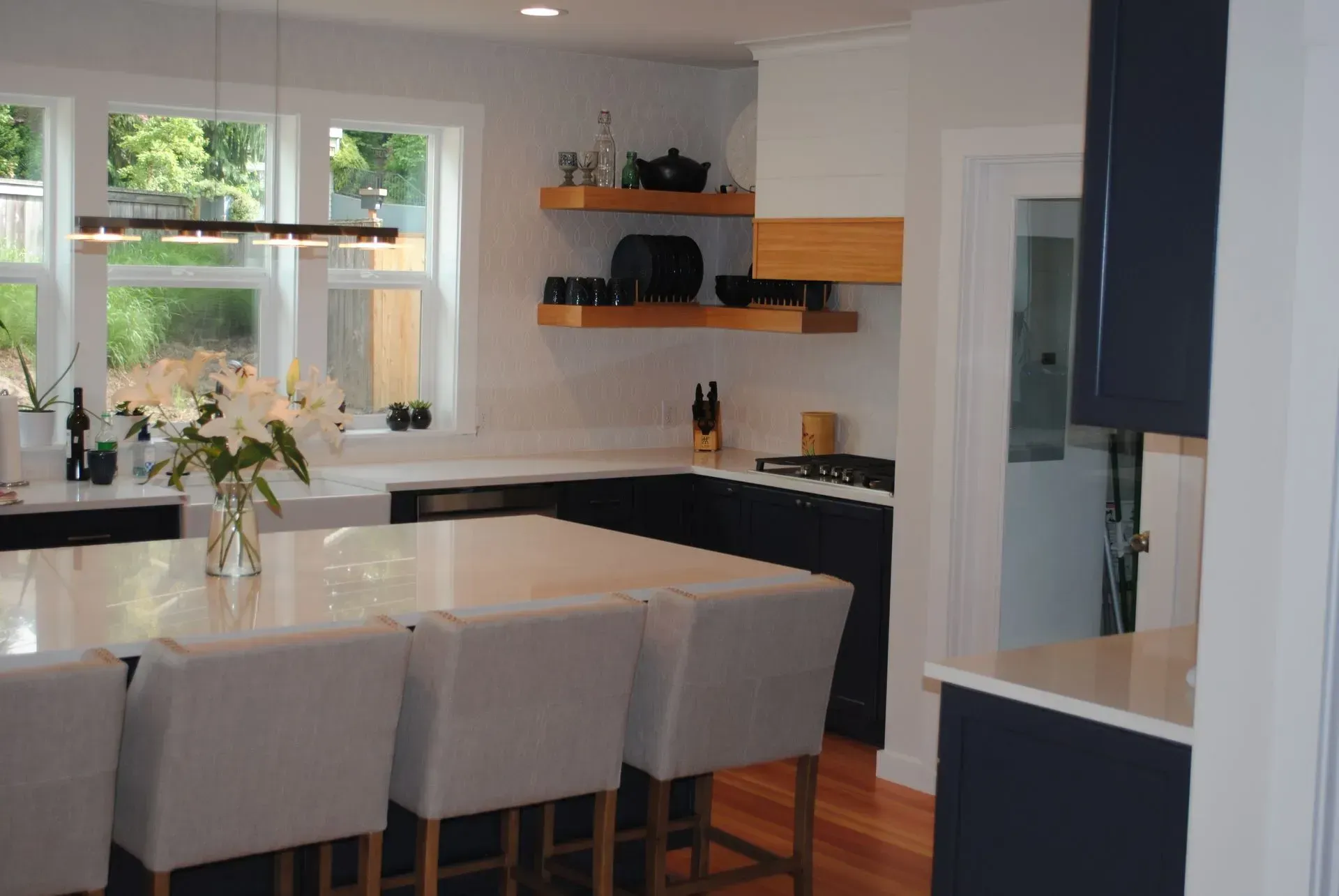 Modern kitchen with a white countertop island, dark blue cabinets, and wooden shelves.