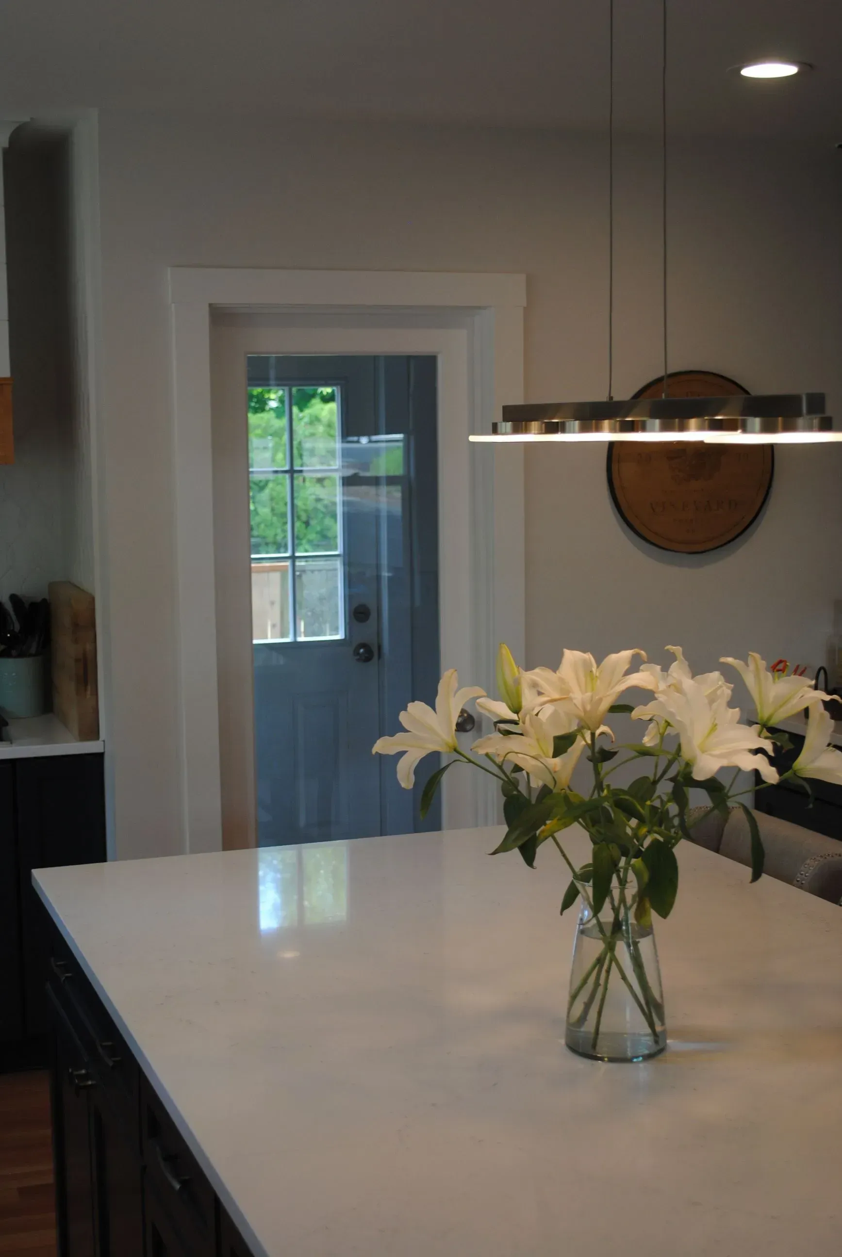 Kitchen island with white countertop, lilies, and a view of a blue door.