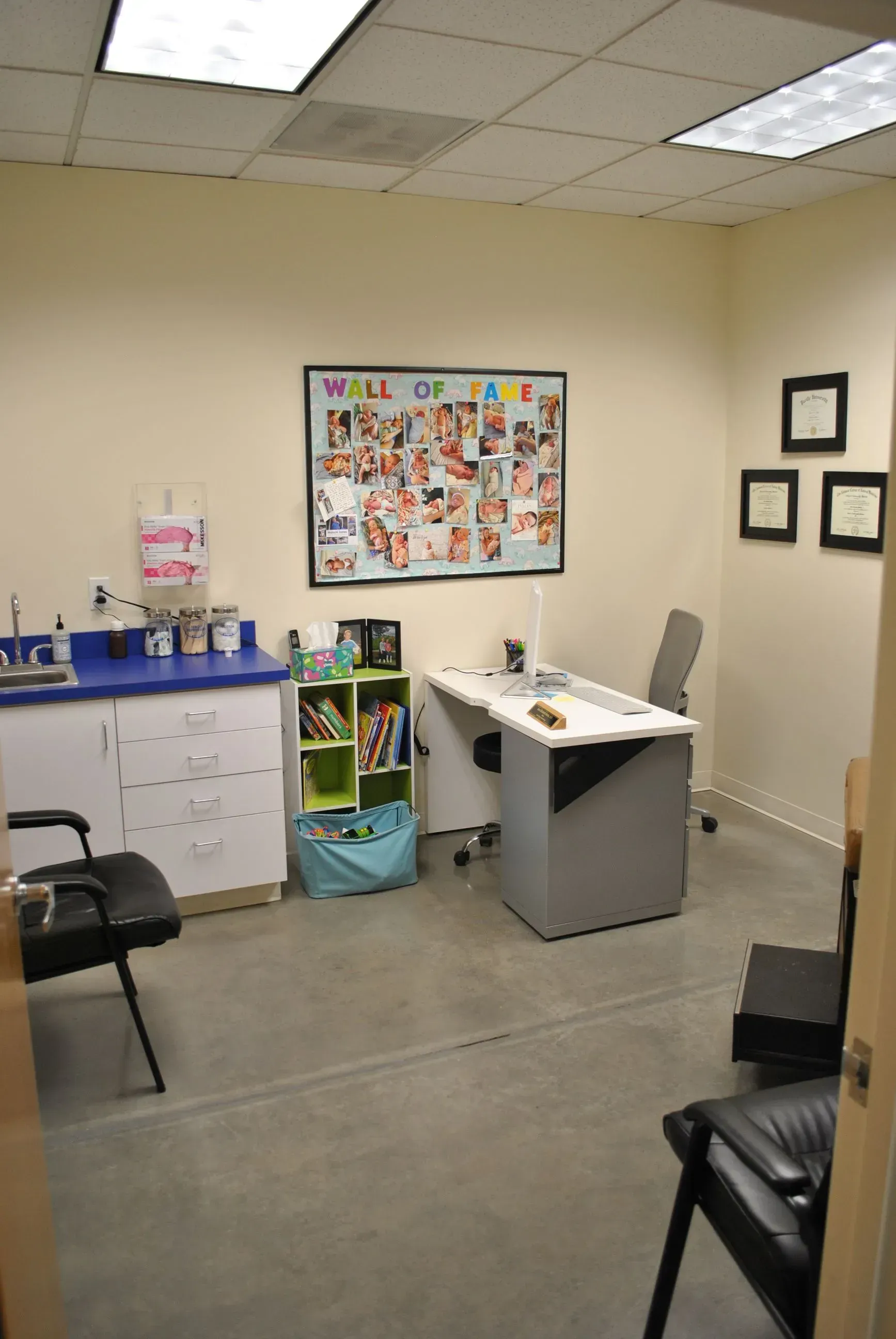 Medical office with desk, cabinets, chairs, and framed artwork.