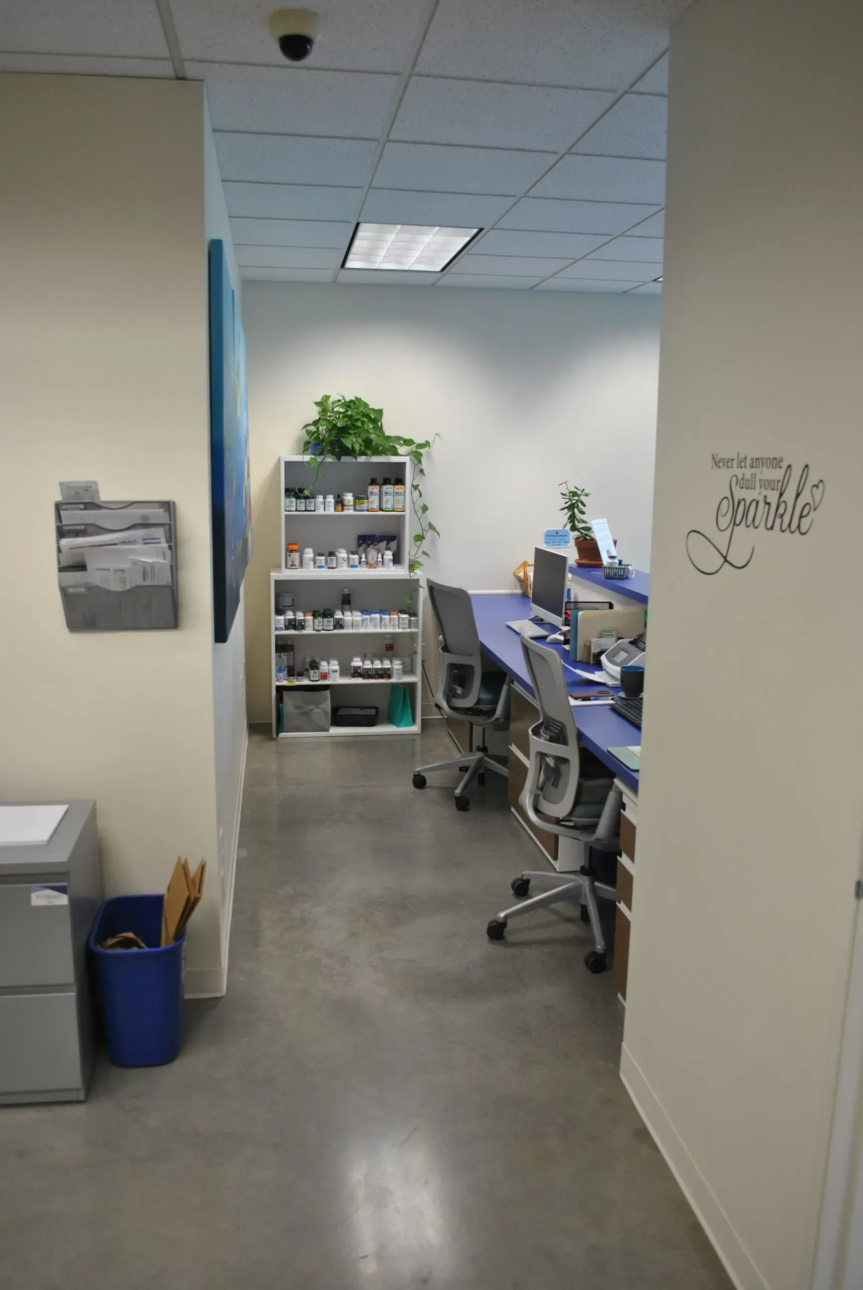 Hallway leading into a medical office with desks, shelves, and a waiting area.