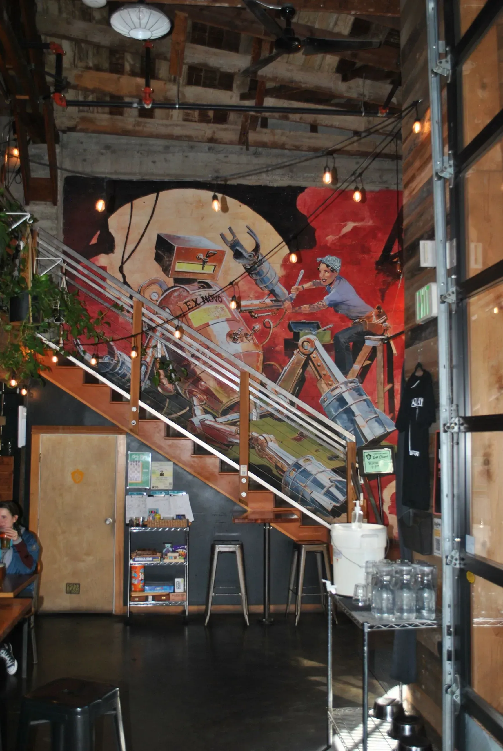 A colorful mural of a robot and person on a staircase inside a restaurant.