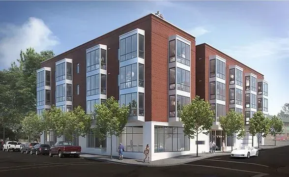 Red brick apartment building with large windows and street-level commercial space; people on sidewalk, cars parked.