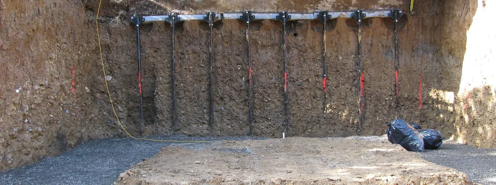 Targets at a shooting range, black support rods, brown concrete wall.