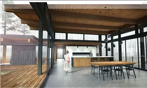 Interior of modern cabin with open layout, wood ceilings, and large windows. Woman walks by kitchen area.
