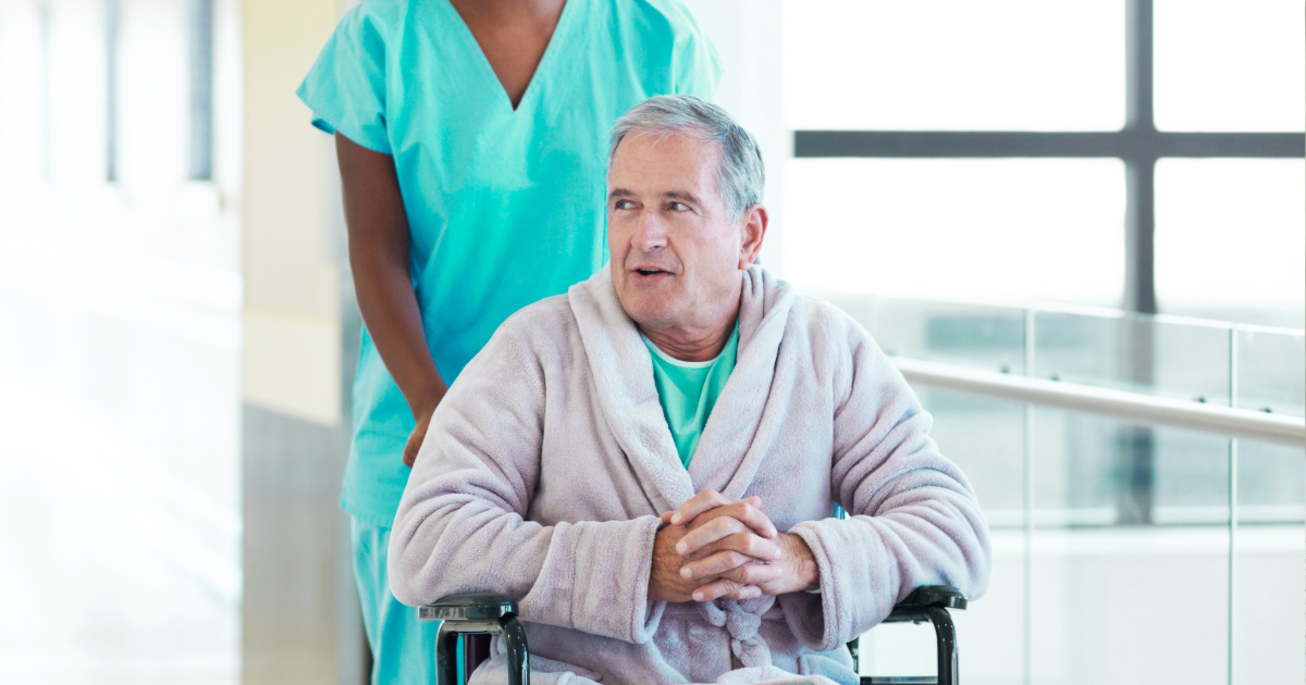 Nurse in blue scrubs holds hands with patient, offering comfort.