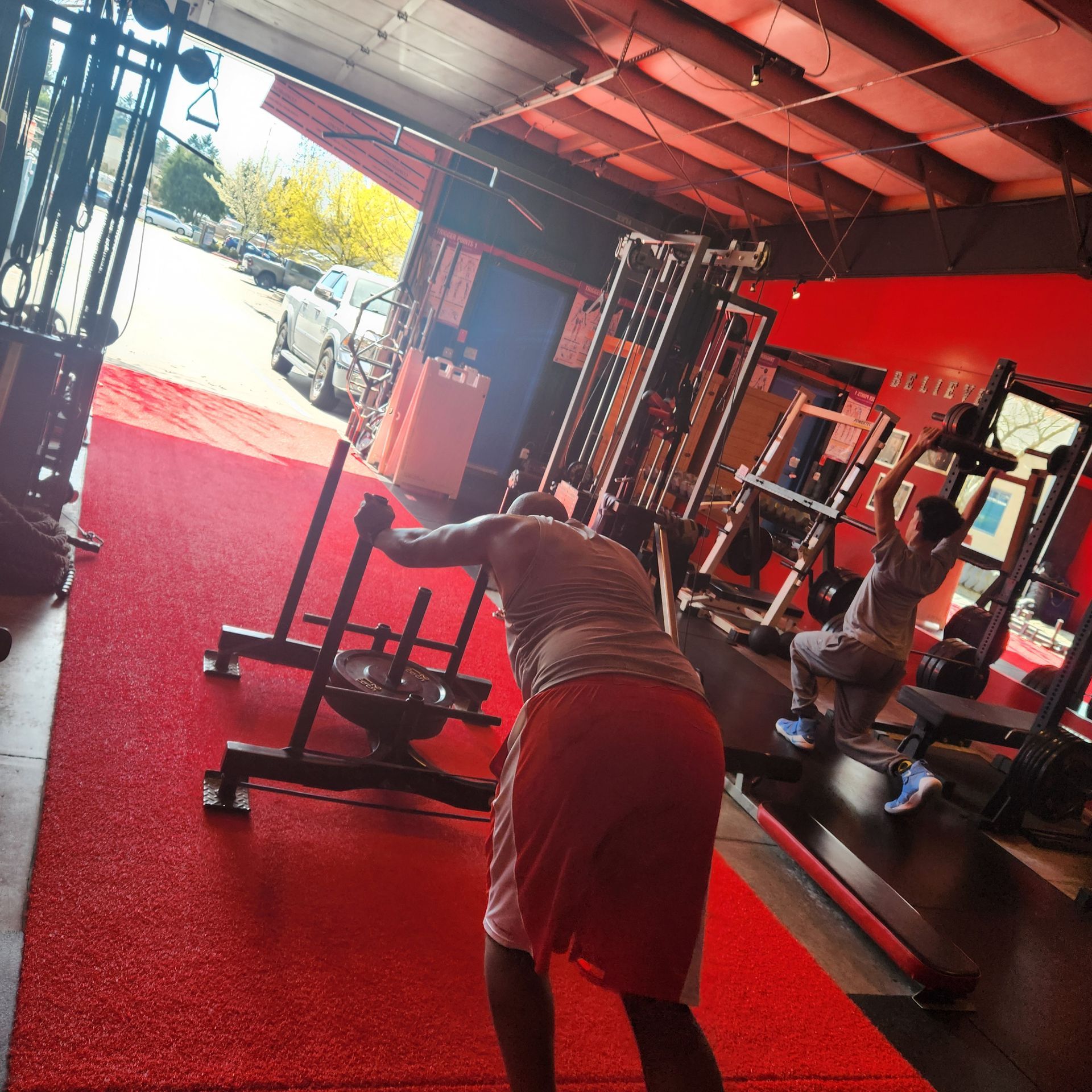 Muscular person with hands behind head, in front of a chalkboard with motivational writing.
