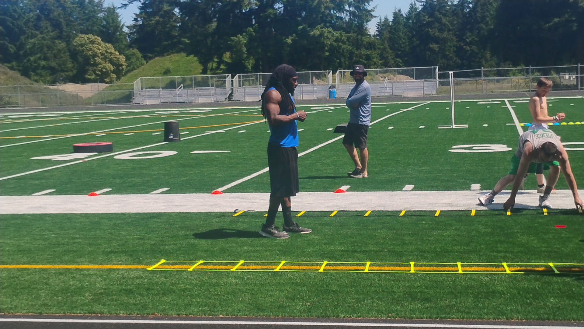 Two people in athletic wear on a green field. They are in a ready stance, near a white line.