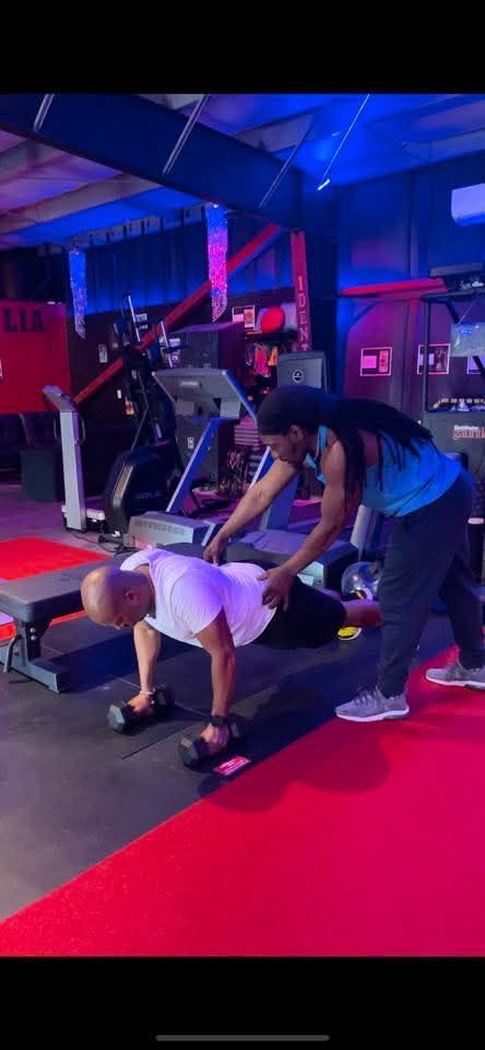 Shirtless person standing in a gym, surrounded by exercise equipment and blue lighting.