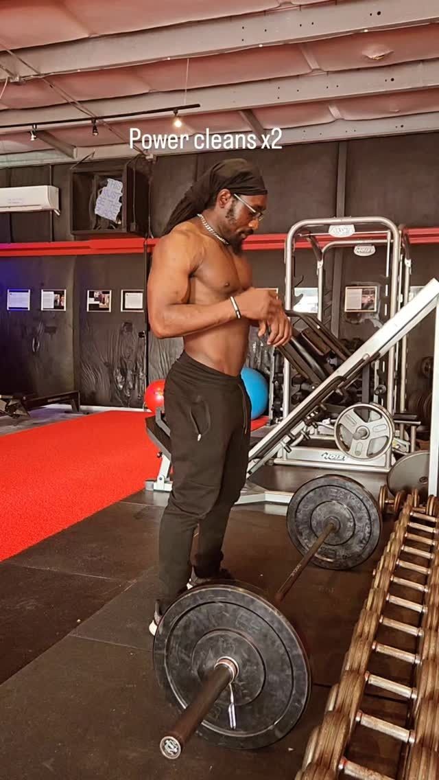 Man in gym, preparing for power cleans with barbell and weights.