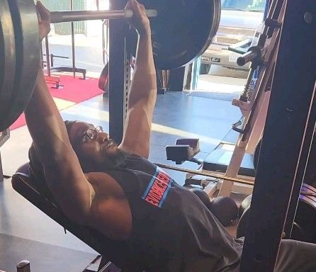 Man lifting weights on an incline bench press in a gym.
