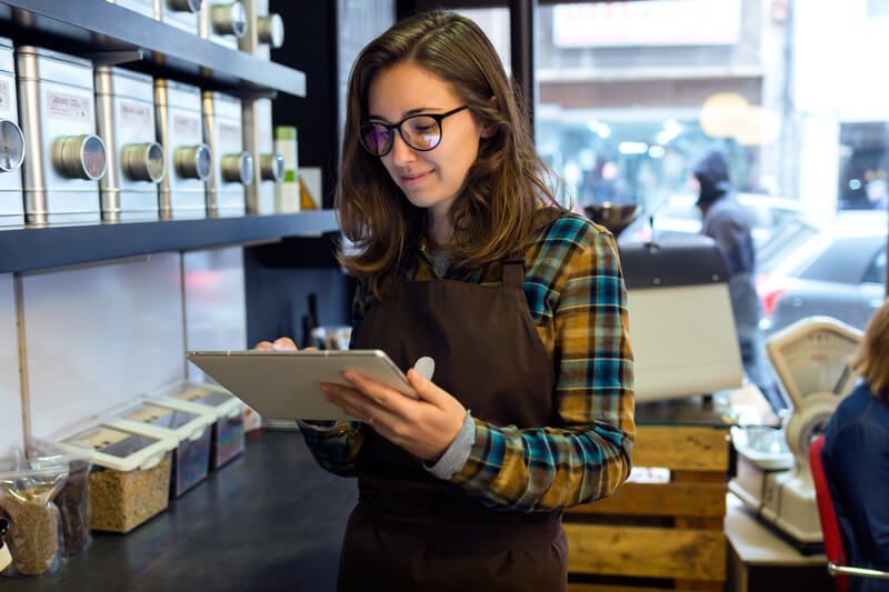 A woman is using a tablet computer in a coffee shop.