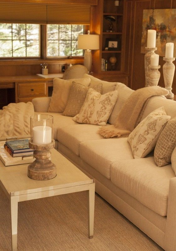 Cozy living room with cream-colored sectional sofa, beige pillows, and a white coffee table.
