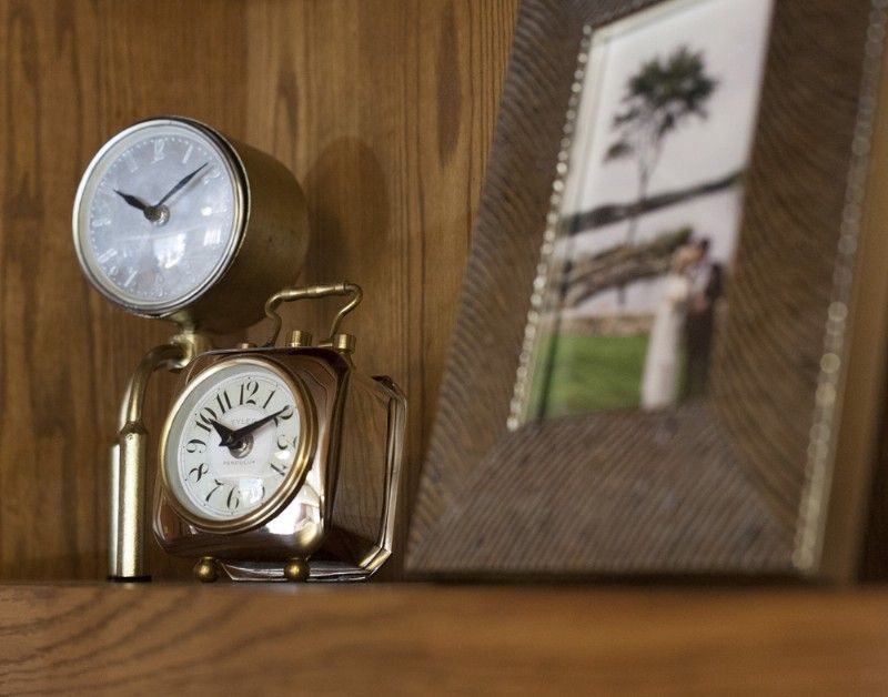 Gold clocks and framed photo on a wooden shelf, with a couple in a landscape.