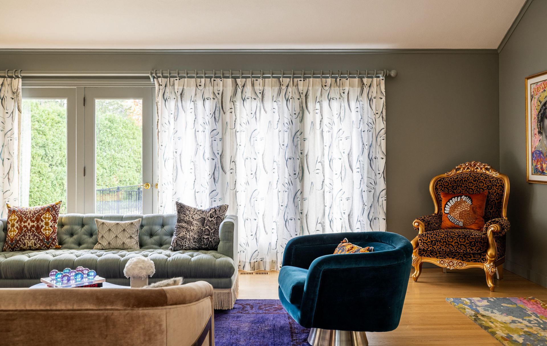 Living room with blue sofa, gold armchair, blue swivel chair, and white patterned curtains.