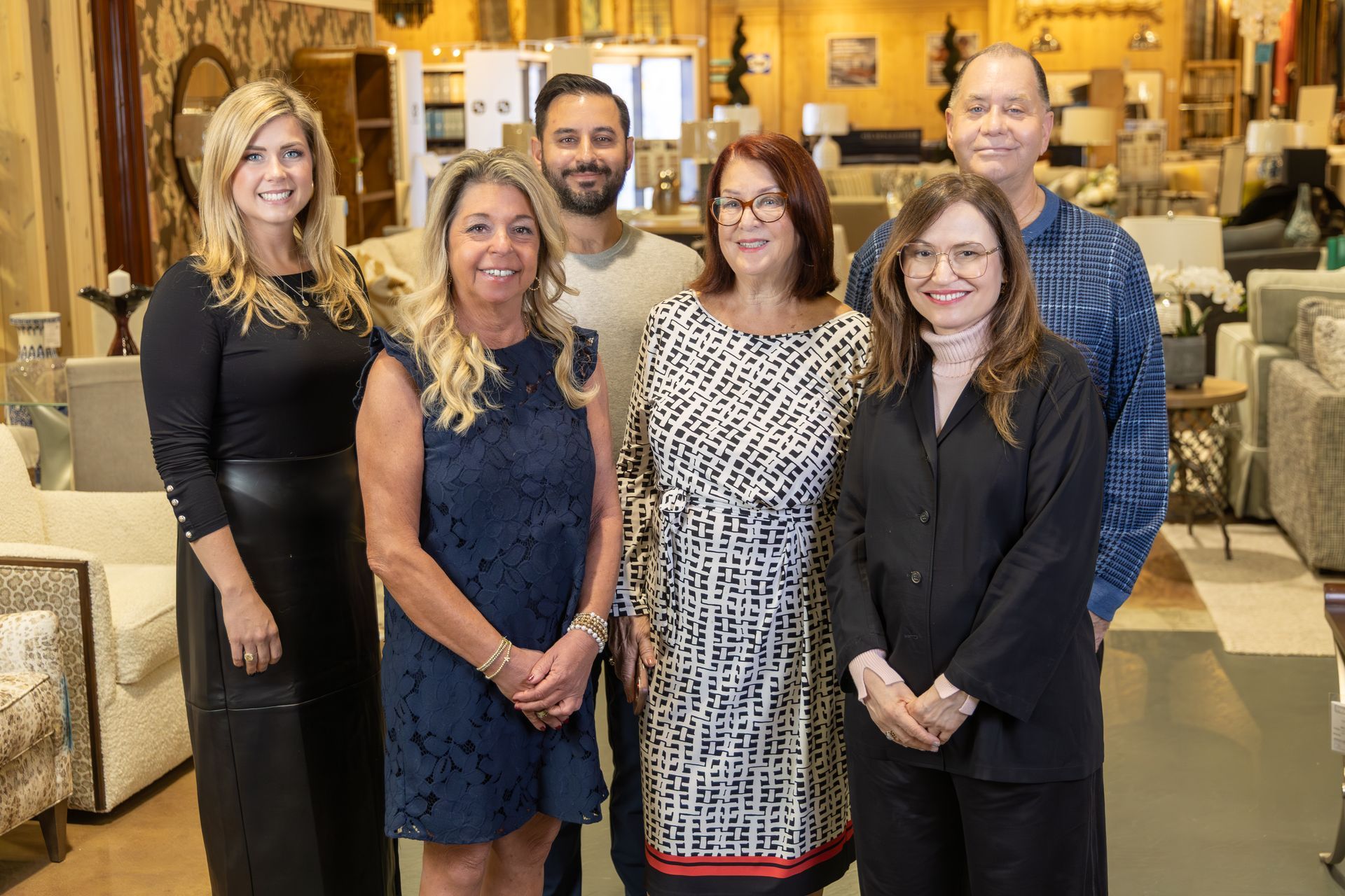 Group of people in a furniture store, smiling at the camera. Store interior in the background.