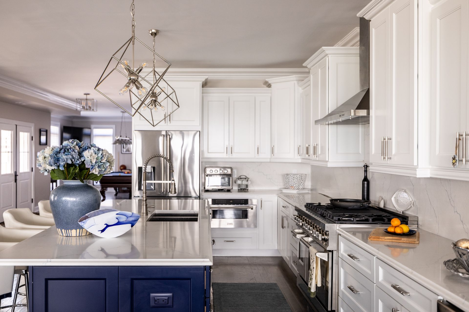 Modern kitchen with white cabinets, stainless steel appliances, and a navy blue island.