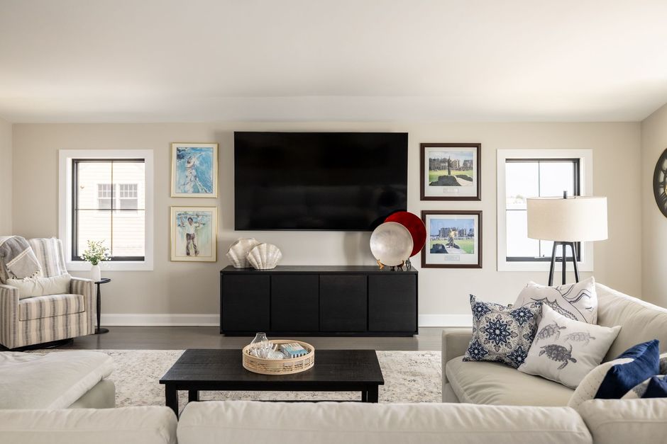 Living room with TV, black console, artwork, and neutral-colored sofa.