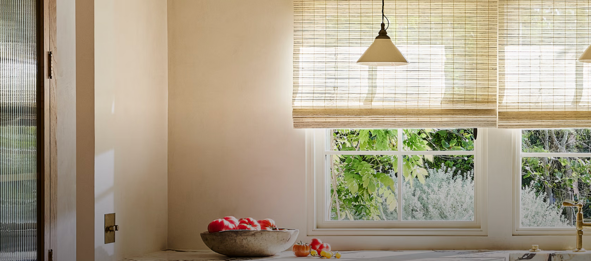 Kitchen with windows, fruit bowl on counter, light fixtures, and natural light.