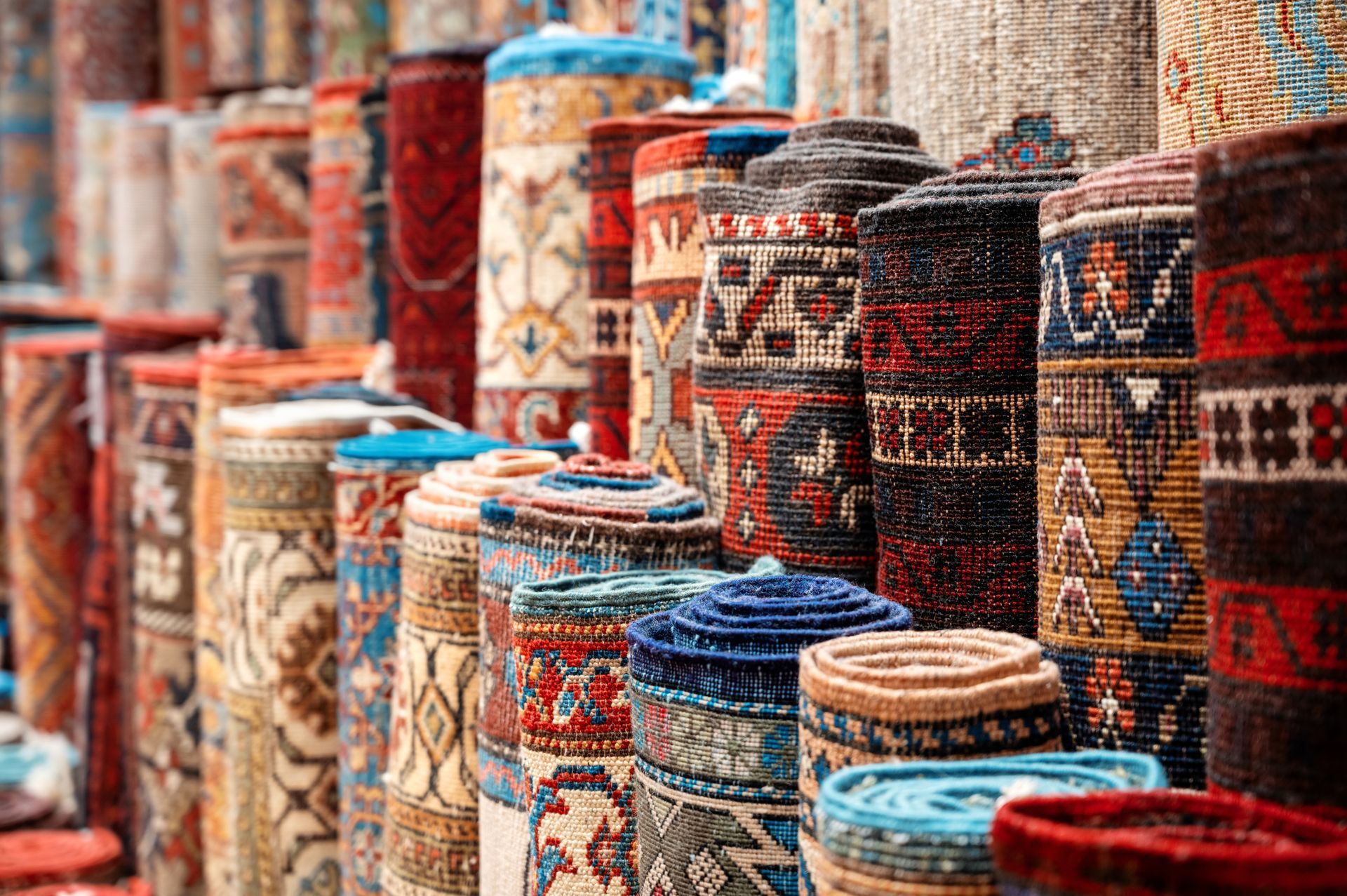 Rolled-up, colorful carpets on display in a shop, showcasing intricate patterns and textures.