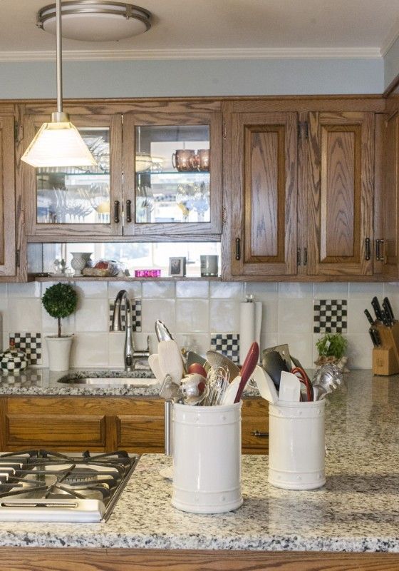 Kitchen countertop with utensils, cabinets, and a stove.