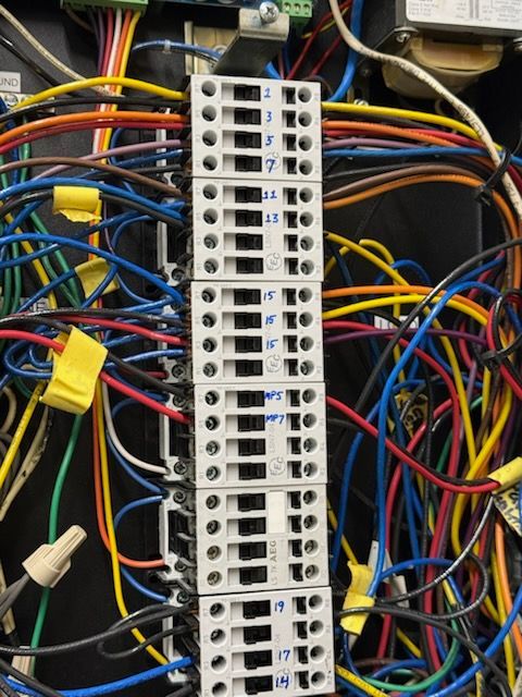 A vertical row of labeled electrical terminal blocks with various colored wires connected to both sides.