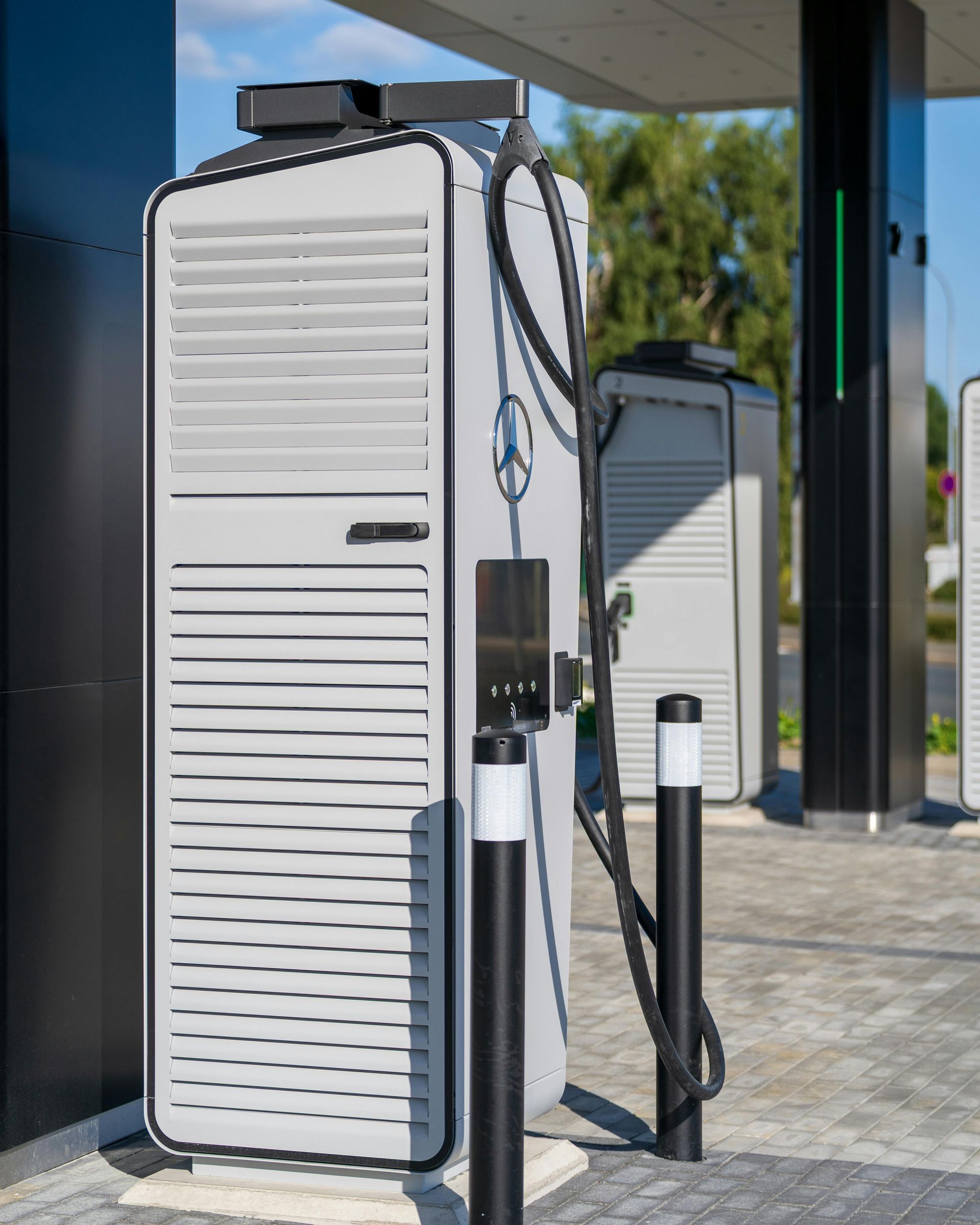 A modern, gray Mercedes-Benz electric vehicle charging station outdoors on a paved lot.