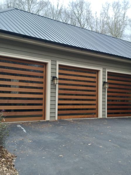 A garage with three wooden garage doors and a metal roof