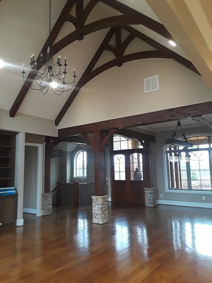 An empty room with a vaulted ceiling and wooden beams